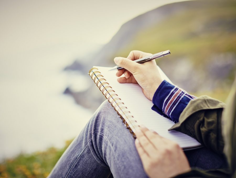 Close-up of a woman writing in a notebook on hillside